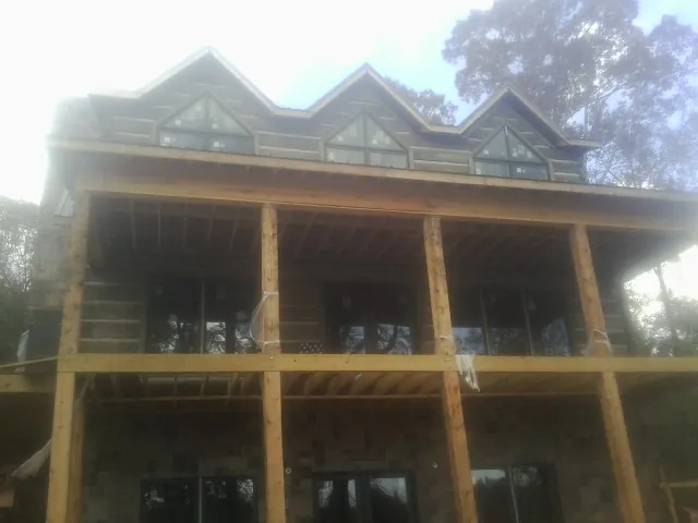 Dormers and porch framing on a large log home under construction — Roof Coating work by our crew in Bonanza