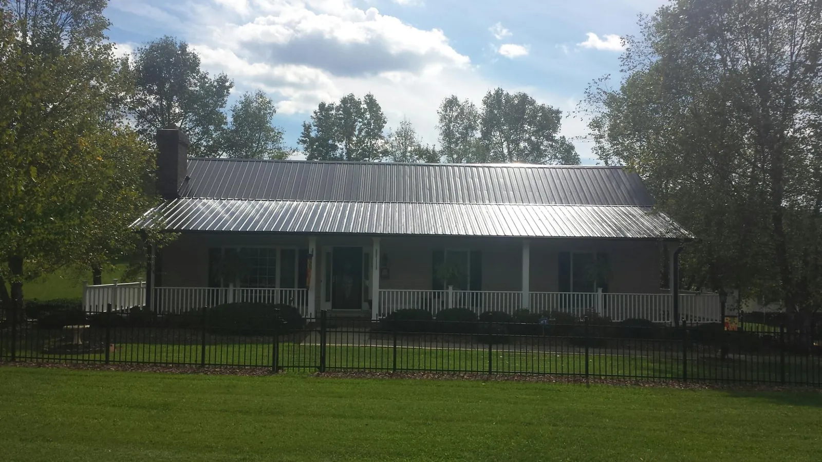 Gray metal roof on a brick ranch with a full width front porch — Gutter Guard Installation work by our crew in Bonanza
