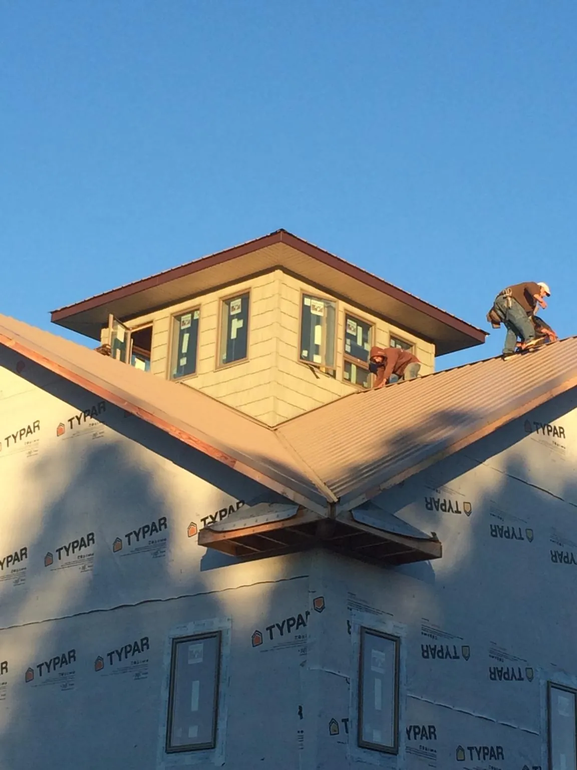 Roofers working around a rooftop cupola on a new metal roof at sunset — Roof Waterproofing in Bonanza by Roofing Brothers